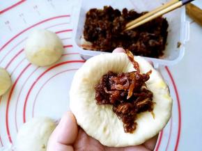 松弛后的面团擀成圆形，翻面后包入馅料；收口捏紧，轻轻按扁，