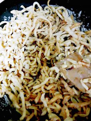 把炸好的面条和剩余的蔓越莓干和芝麻倒入锅中，小火，翻拌使面条均匀的裹上糖浆，关火再拌几下