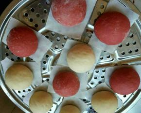 将两种颜色的面团，分别分成6等份，其中每个颜色的面团留一个，用来制作鼻子和耳朵，剩下的揉圆码入蒸屉中