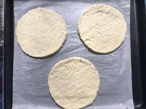 在圆披萨底上用小叉叉出小洞，并轻轻喷洒少量的水