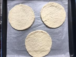 在圆披萨底上用小叉叉出小洞，并轻轻喷洒少量的水