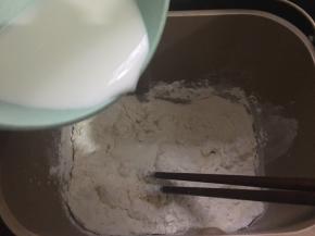 饼底材料中的高粉、低粉、盐、糖和酵母倒入面包机桶里，加入纯牛奶，用筷子搅拌成棉絮状