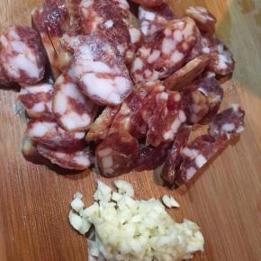 腊肠用开水烫洗干净，切薄片，蒜头切碎。