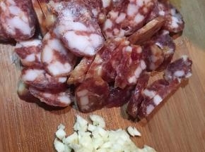 腊肠用开水烫洗干净，切薄片，蒜头切碎。