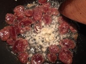炒至腊肠表面微焦，下入蒜末煸出香味。