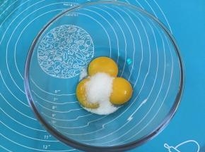 4. 在蛋黄糊中加人细砂糖，用手动打蛋器搅拌
