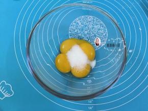 2. 在蛋黄糊中加人细砂糖，用手动打蛋器搅拌