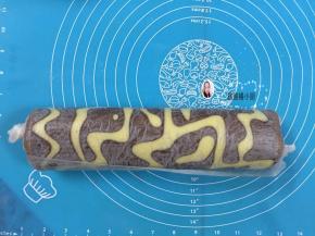 17. 出炉后从20厘米高的地方震一下，把热气震出，倒扣在烤网上，趁热把油纸撕下，把蛋糕卷好像包糖一样包着，让其定形