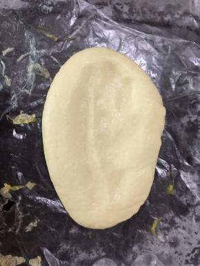 发酵好的面饼放在铺有油纸的烤盘上，用手指轻轻按压面饼中间