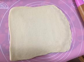 然后用擀面杖将面团擀成长方形，再将面团翻面，用手指在一端轻轻按出略薄的指印