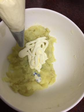 将蒸熟的土豆压成泥后挤入打发好的奶油一起搅拌均匀