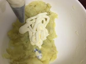 将蒸熟的土豆压成泥后挤入打发好的奶油一起搅拌均匀