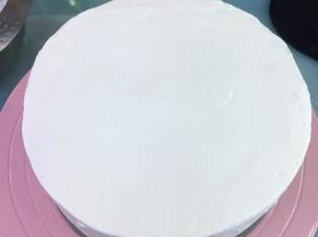 盖上另一片蛋糕片，在蛋糕表面和周边都抹上奶油。