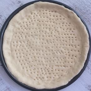 披萨盘抹油，将发酵好的面团，用擀面杖擀成与盘底一样大小的饼底，把饼皮铺进去，用叉子叉小孔。