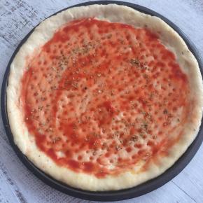 披萨饼底抹一层番茄酱，再撒一些披萨草。