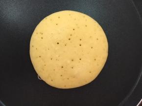 大约两分钟，玉米面饼底部凝固成金黄色，晃动锅，玉米面饼能在锅里滑动，即可翻面