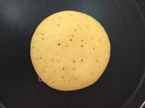 大约两分钟，玉米面饼底部凝固成金黄色，晃动锅，玉米面饼能在锅里滑动，即可翻面