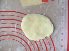 把这个面团竖着，用大拇指在中间按压，将两头的卷挤到中间，然后按扁，擀开