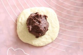 取一个面团，按扁包入豆沙馅。