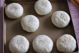 依次放入烤盘，面团中间轻刷一层水，然后面杖一端沾水沾白芝麻在面团中间按一下，依次做好，保鲜膜覆盖二次发酵（室温28度40分钟）。