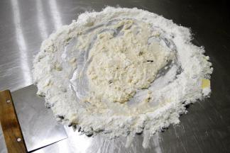 将周围的面粉向中间勾入混合，混合到中间不流动时，用刮板收起周围材料，混合按压