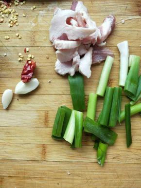 大肉切片，干辣椒捏开去仔，小葱切断，新蒜剥皮切两半。