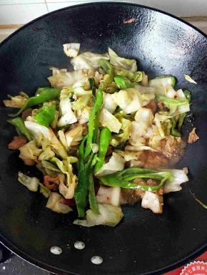 倒入包菜和青椒翻炒，食材变软加入盐，花椒，鸡精调味关火。