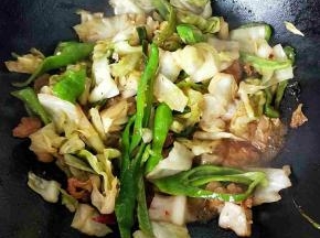 倒入包菜和青椒翻炒，食材变软加入盐，花椒，鸡精调味关火。
