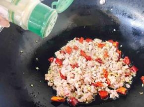 然后放入肉末，用铲子把肉末打散，翻炒几下，肉末变色后加入少许白胡椒粉和少许料酒且翻炒均匀。
