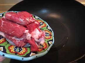 倒入牛肉片和洋葱片翻炒。