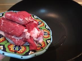 倒入牛肉片和洋葱片翻炒。