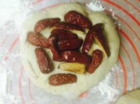 面团压扁排气，包入之前准备好去核儿的红枣，像包包子一样给它包起来