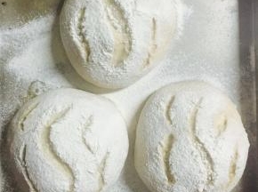 取出发好的面包，筛上一些高筋面粉。用割刀在面包表面割出你喜欢的图案