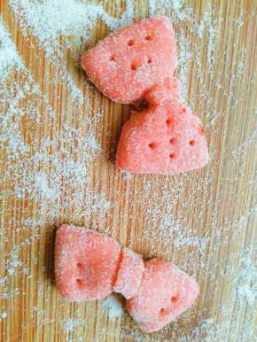 另取一点面团加少许红曲粉揉匀擀开，切成长方形面片，用筷子夹住中间做出蝴蝶结，还可以用牙签插几个孔做装饰