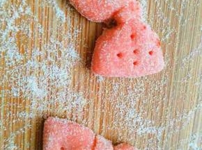 另取一点面团加少许红曲粉揉匀擀开，切成长方形面片，用筷子夹住中间做出蝴蝶结，还可以用牙签插几个孔做装饰