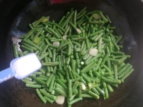 倒入豆角煸炒几下，放入1勺盐，1勺生抽。
