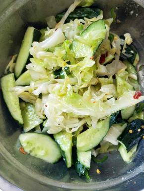 控干水分的橄榄菜和青椒倒入装黄瓜的盆里。放入干辣皮，葱，蒜末，鸡精。放入调料，调料上倒入烧热的植物油。