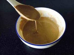 第一步，调制芝麻酱酱汁。
把100g的芝麻酱放在一个大点的碗里，用100g的凉白开水分批分次加入到芝麻酱里，并且每加一次水就要把它搅拌均匀，一直调到如图所示，用小勺往外倒酱汁较为顺滑又有些粘稠状态。