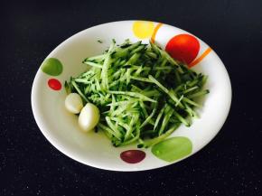 在煮面时，我们把黄瓜切成丝，剥好蒜备用。
