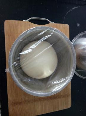 2、揉好的面团取出，放案板上摔一摔，揉一揉，揉出手套膜，放盆里，盖保鲜膜放在温暖处进行基础发酵。