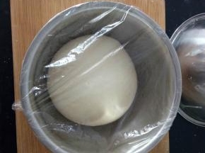 2、揉好的面团取出，放案板上摔一摔，揉一揉，揉出手套膜，放盆里，盖保鲜膜放在温暖处进行基础发酵。