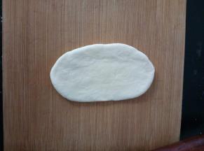 6.	取一份面团，光面向上，拍几下排气，然后擀成椭圆形。