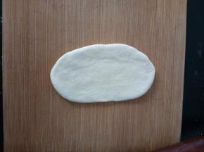 6.	取一份面团，光面向上，拍几下排气，然后擀成椭圆形。