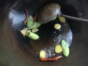 锅坐火上，烧热倒入适量油，差不多和炒菜一样多就好了，下入葱姜煸炒出香味。