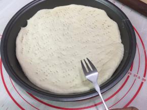 11. 将面团按圆按扁成饼状，尽量让饼皮的厚度均匀，把饼皮用叉子在饼皮上扎满小孔