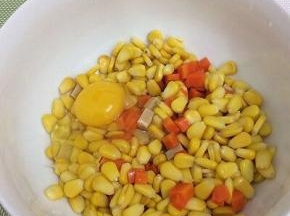 将玉米粒、胡萝卜和火腿肠装入碗中，加入鸡蛋，搅拌均匀
