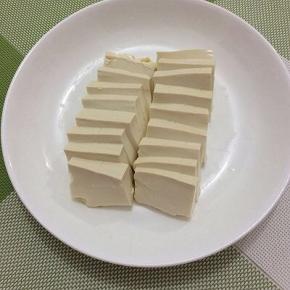 将豆腐洗一下，切成薄片，摆在盘中