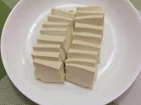 将豆腐洗一下，切成薄片，摆在盘中