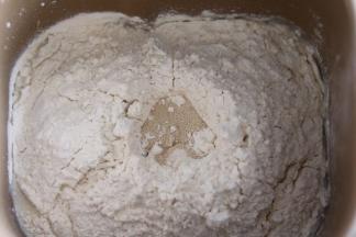 面团原料除黄油外，全部放入面包机桶，启动面包机和面程序。