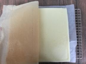 用一张干净的油纸盖在蛋糕表面，翻过来，揭开油布。